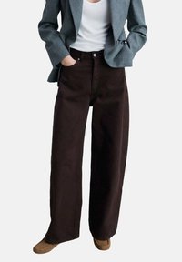 Ruskeat capri-mittaiset farkut korkealla vyötäröllä ja etutaskuilla, yhdistettynä valkoiseen topiin ja harmaaseen bleiseriin. Sileä farkkukangas.