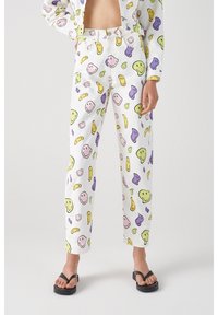Pantalones blancos con un patrón divertido de caras sonrientes de colores y formas abstractas en amarillo, verde, púrpura y rosa. Corte de pierna recta.