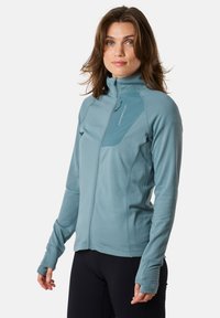 Light blue zip-up jacket made of soft material, featuring a high collar, thumbholes, and a chest pocket with a contrasting panel.