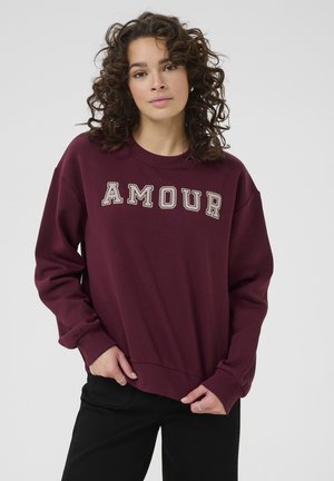 Sweatshirt bordeaux avec le texte "AMOUR", col rond, manches longues, poignets et ourlet côtelés, en tissu doux, avec une coupe décontractée.