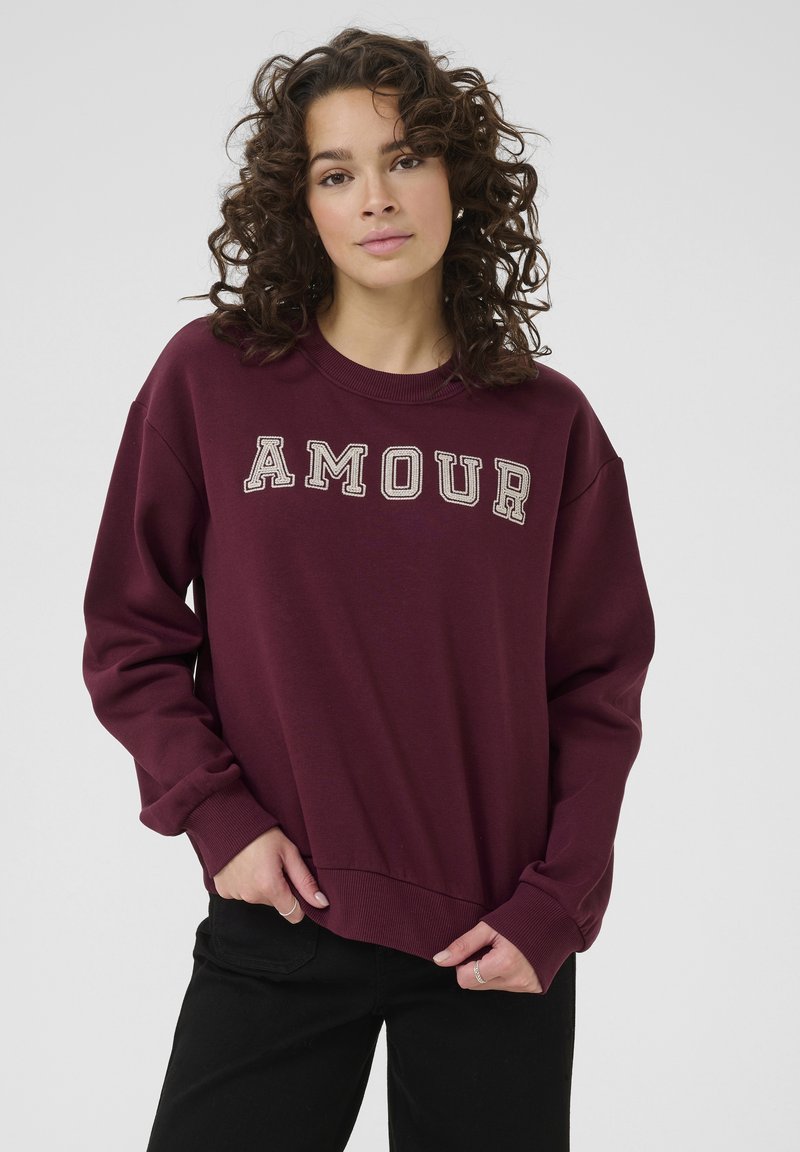 Felpa bordeaux con testo "AMOUR", collo rotondo, maniche lunghe, polsini e orlo a costine, realizzata in un tessuto morbido, caratterizzata da una vestibilità comoda.