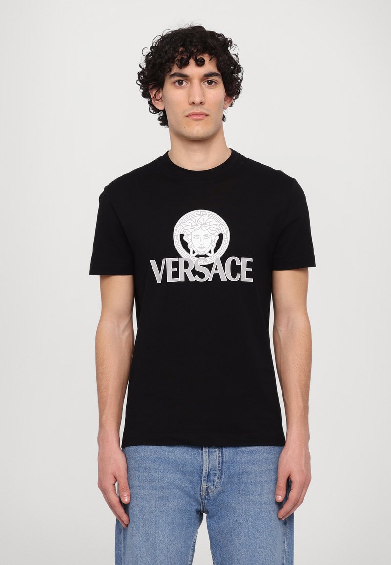 Sort bomulds T-shirt med rund halsudskæring, korte ærmer og et frontlogo med et græsk motiv samt ordet "VERSACE" i hvid.