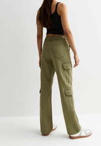 Olijfgroene cargo broek met meerdere zakken, een rechte pijpdesign, gemaakt van een katoenmix, gecombineerd met witte sneakers en een zwarte tanktop.