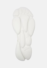 Suola della scarpa in gomma bianca, caratterizzata da una superficie testurizzata con sezioni rialzate e un logo centrale. Progettata con forme arrotondate ed ergonomiche.