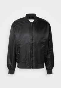 Veste bomber en satin noir avec fermeture éclair à l'avant, deux poches à rabat avec boutons-pression, poignets, col et ourlet côtelés.