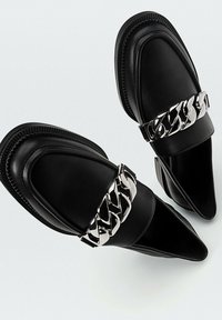 Mocassini in pelle nera con punta affusolata, dotati di un accento in catena metallica sul dorso del piede e suola in gomma texturizzata.