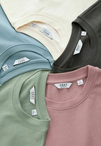 Four t-shirts in varying colors: light blue, green, pink, and beige. Each features a crew neck and is made from soft cotton material.