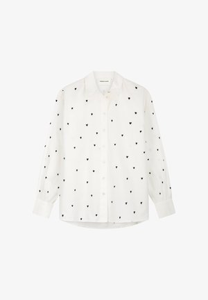 Witte blouse met lange mouwen en knopen, bedrukt met kleine zwarte hartjes verspreid over de stof.