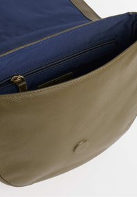 Borsa in pelle verde oliva con finitura testurizzata, con fodera blu marino e una tasca con zip all'interno. Chiusura a pressione rotonda all'esterno.
