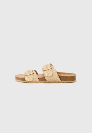 Sandale slide tissée beige avec semelle en liège et deux brides à boucle réglables, présentée sur un fond uni clair.