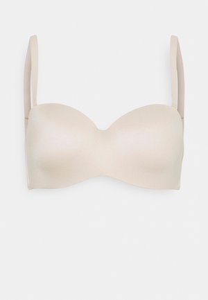 Soutien-gorge beige sans bretelles avec texture lisse et coques légèrement rembourrées, dotée de fines bretelles ajustables et de bordures sans coutures pour un look épuré.