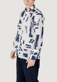 Witte shirt met abstracte navyblauwe patronen, met een button-down kraag en lange mouwen met contrasterende manchetten.