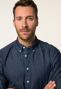 Koszula dżinsowa w ciemnoniebieskim kolorze z kołnierzykiem zapinanym na guziki, z jasnoniebieskimi guzikami i gładką fakturą. Koszula jest starannie włożona.