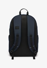 Mochila azul marino con panel trasero de malla negra, con correas acolchadas y forma rectangular. Etiqueta del logo en la parte superior de la espalda, diseño minimalista.