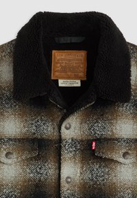 Brązowa i czarna koszula flanelowa w kratę z kołnierzem z owczej wełny, zapięciem na guziki, kieszeniami z przodu i skórzaną metką z logo Levi's.