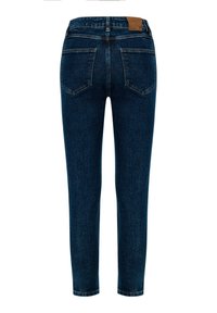 Tmavě modré džíny s užším střihem, pěti kapsami a koženou nášivkou na pase. Prošívání kontrastuje s barvou látky.