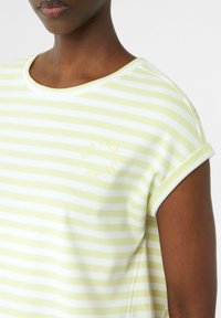 Gestreept T-shirt van zachte katoen, met lichte gele en witte horizontale strepen, een ronde halslijn en omgeslagen korte mouwen met subtiele logo-details.