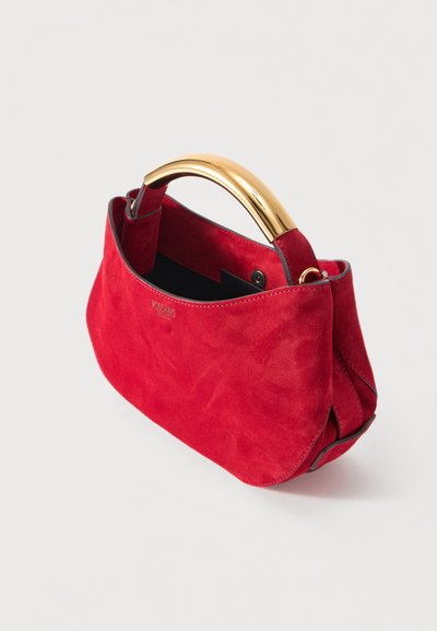 Κόκκινη τσάντα χειρός από σουέτ με καμπυλωτή χρυσή μεταλλική λαβή, μαύρη εσωτερική επένδυση και διακριτικό λογότυπο της μάρκας στο πλάι.