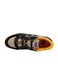 Sneaker med en beige tygöverdel, svarta mockadetaljer, gula snören och en vadderad svart tunga. Har en lila logotyp på innersulan.