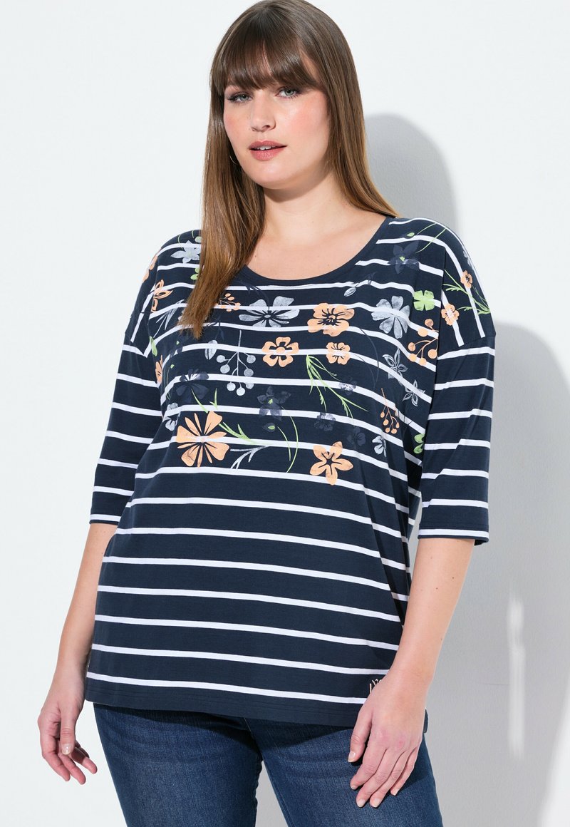 T-shirt a righe navy e bianche con ricami floreali in grigio, pesca e verde; presenta un collo a barca e una vestibilità ampia, maniche a tre quarti.