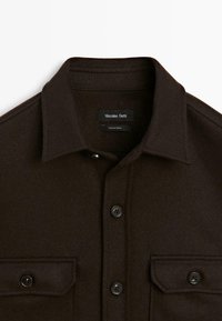 Donkerbruine overhemd met knopen, voorzien van twee borstzakken en een gespreide kraag, gelabeld Massimo Dutti, gemaakt in Turkije.