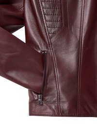 Giacca in pelle bordeaux con tasca con zip, pannelli testurizzati sulle spalle e finitura liscia. Dettagli ravvicinati delle maniche.