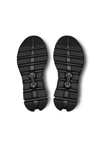 Les semelles des chaussures de sport noires présentent des textures multidirectionnelles, des rainures pour l'adhérence et un accent de logo central. Conçues pour la durabilité et la prise.
