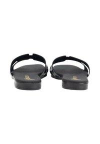 Sandalias planas negras con un acabado liso y mate. Cuenta con dos tiras delgadas y una planta contorneada. Diseño minimalista, sin herrajes visibles.