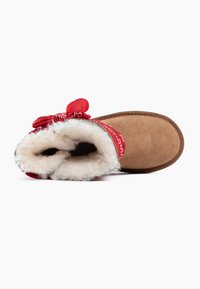 Pantofole in suede marrone con un accento di bandana rossa in tessuto, foderate in finta pelliccia crema, punta rotonda e suola piatta. Dettagli di design accessibili inclusi.