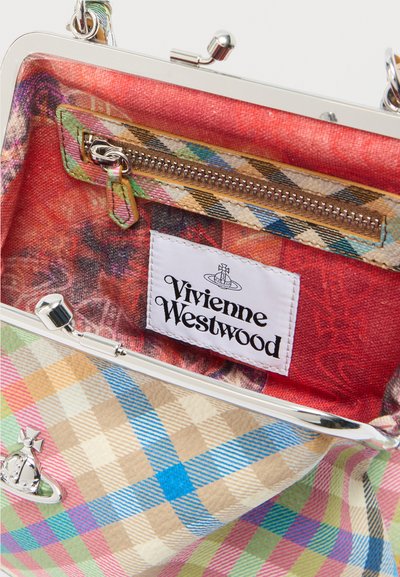 Színes kockás szövet táska belseje ezüst kapoccsal, piros mintás béléssel és cipzáras zsebbel, amelyen színes címke található.