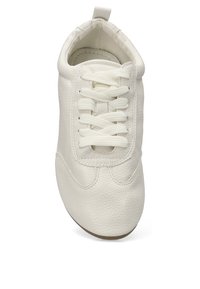 Zapatilla de piel blanca con punta redondeada, textura suave y cordones planos. Su diseño simple incluye acentos de costura y una tira en el talón.