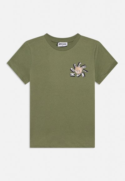 Camiseta de manga corta color verde oliva con cuello redondo, pequeño gráfico de oso de peluche y texto "MOSCHINO" en el lado izquierdo del pecho.