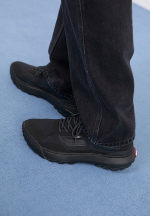 Mustmustad mustrenna kingad tekstureeritud ülaosaga, tugevdatud varvastega ja kummist välispinnaga. Paelad sobivas värvitoonis ja logo detail külje peal.