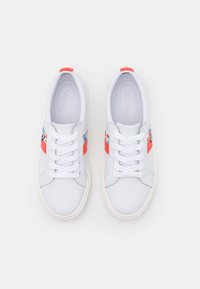 Vita sneakers med en slät läderöverdel. Har röda detaljer och en flerfärgad design på sidorna, med en texturerad vit gummisula.