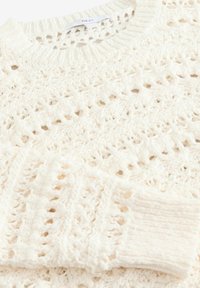 Pull blanc en tricot avec motif ajouré et poignets côtelés, plié pour montrer la manche et l'encolure avec l'étiquette de la marque "NEXT".