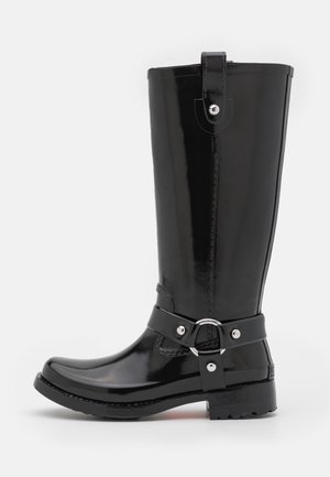 Botte haute en caoutchouc noir brillant avec une bride décorative et un anneau métallique, semelle plate et bout rond.