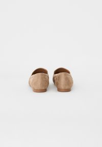 Suede slip-on shoes in light brown with a low back and rounded toe. Features a smooth texture and a simple design.