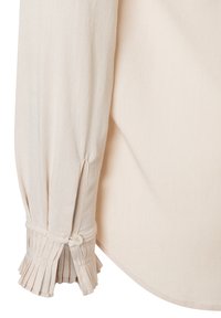 Blassbeige Bluse mit langen Ärmeln, die einen knöpfbaren Bund mit vertikalen Falten und eine glatte, weiche Textur bietet. Der abgerundete Saum sorgt für eine lässige Passform.