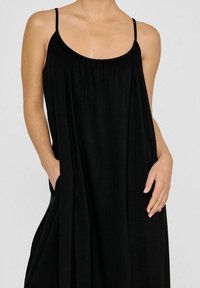 Schwarzes ärmelloses Kleid mit lässiger Passform, Rundhalsausschnitt, gerafften Details und seitlichen Taschen, aus leichtem, weichem Stoff gefertigt.