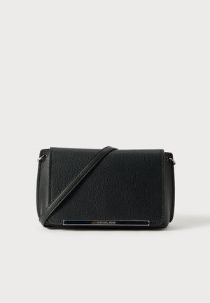 Sac bandoulière en cuir noir avec rabat avant et fine sangle ajustable reposant en diagonale sur le sac sur fond blanc.
