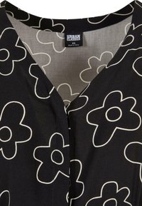 Črna bluzica iz tkanine z velikimi belimi cvetličnimi vzorci, V-izrezom in oznako "Urban Classics, XS." Gladka tekstura.