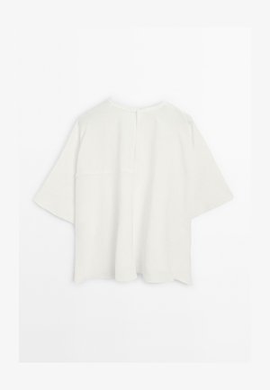 White, oversized short-sleeve top with a simple round neckline and back seam detail, displayed against a plain white background.
