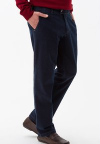 Jeans in denim blu scuro con taglio dritto, dotati di tasche anteriori e chiusura a bottone classica. Tessuto testurizzato con dettagli di cucitura minimi.