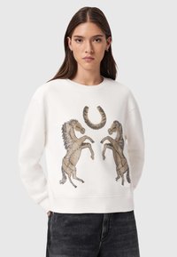 Λευκό φούτερ με ανάγλυφο σχέδιο δύο ίππων που σηκώνονται και έναν πέταλο σε χρυσούς και καφέ τόνους. Μαλακό ύφασμα με ριμπ τελειώματα στα μανίκια.