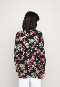 Long-sleeve blouse in black fabric adorned with colorful floral print. Features a relaxed fit and subtle textured design.