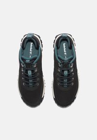 Zapatillas deportivas negras con parte superior de malla texturizada, acentos en teal y cordones circulares. Diseño ligero con una suela de goma resistente.