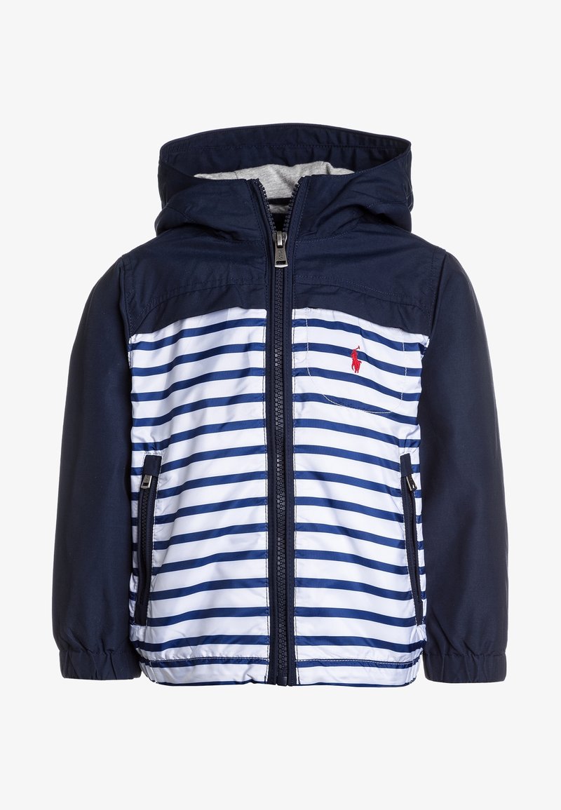 Námořnicko-modrý pruhovaný kabát s kapucí, vybavený zipem vpředu a dvěma bočními kapsami. Materiál vypadá lehký a hladký. Červený logotyp jako detail.