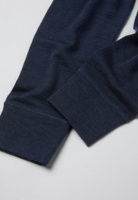 Twee marineblauwe manchetten van een lang mouwenshirt met zichtbare ribgebreide textuur en stiksels op een lichtgrijze ondergrond.