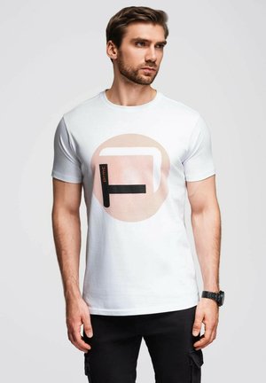 T-shirt bianca in cotone con un grande grafico circolare in rosa e nero, con il testo "prmc" e un design moderno. Maniche corte, colletto tondo.