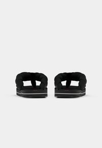 Svarta flip-flops med flätad remdesign, med en texturerad fotbädd och tjock sula med grå accent.